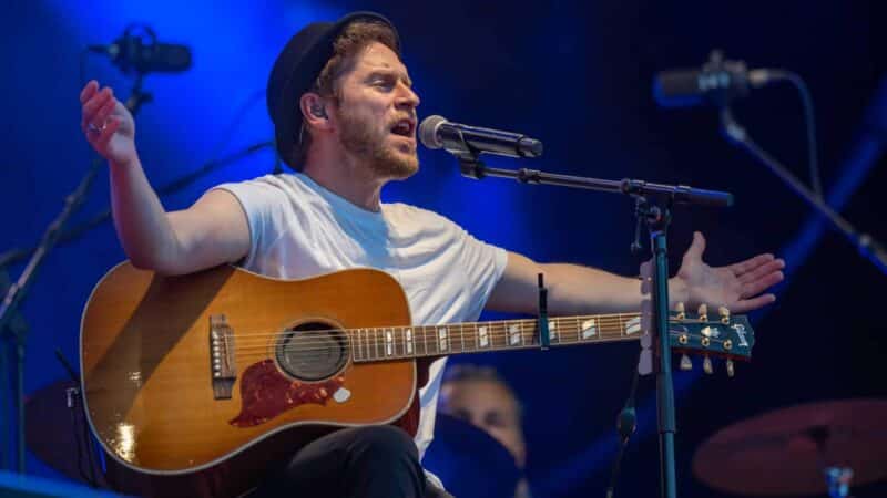 Mann mit Gitarre singt auf einer Bühne.