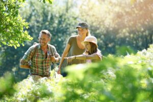 Drei Personen beim Wandern in der Natur, umgeben von grünen Pflanzen.