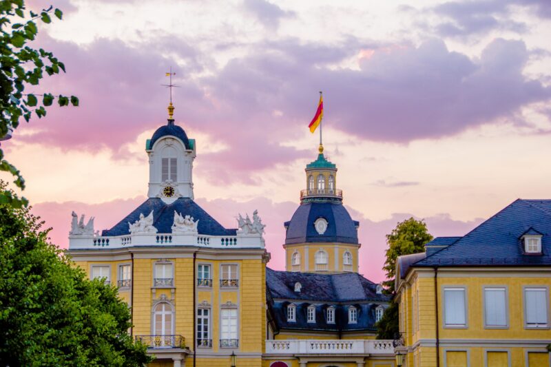 Historisches Gebäude mit deutscher Flagge und buntem Himmel.