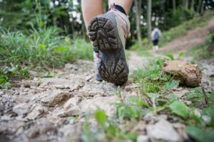 Nahaufnahme eines Wanderschuhs auf einem unebenen Weg.