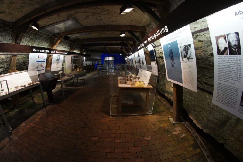 Ausstellung über Kernenergie in einem historischen Raum mit Informationsplakaten.