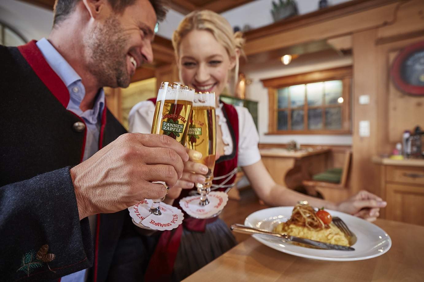 Mann und Frau stoßen mit Biergläsern in einem gemütlichen Restaurant an.