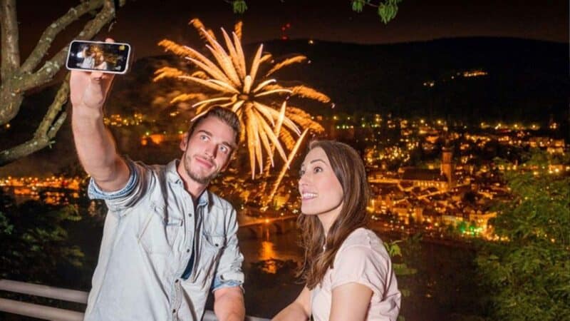 Paar macht ein Selfie vor einem Feuerwerk in der Nacht.