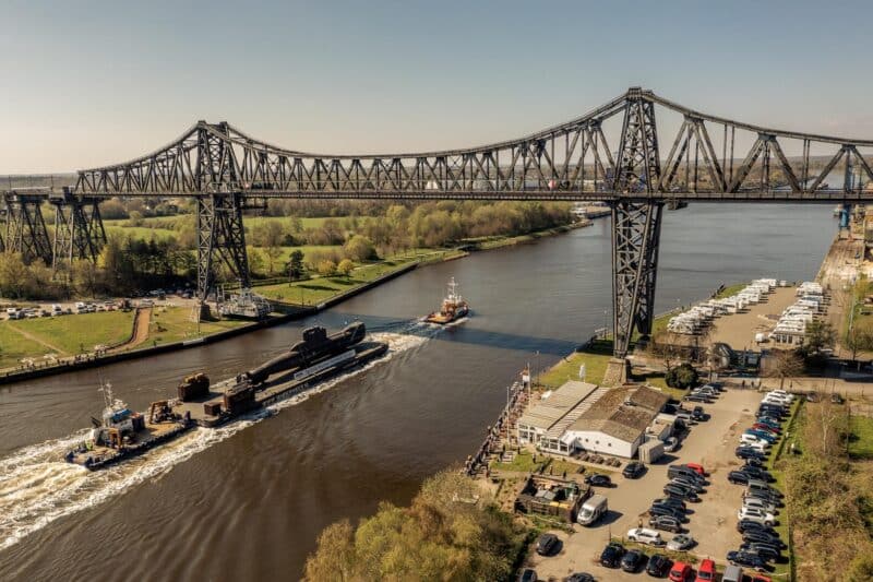 Blick auf eine Brücke über einen Fluss mit Schleppern und Booten.