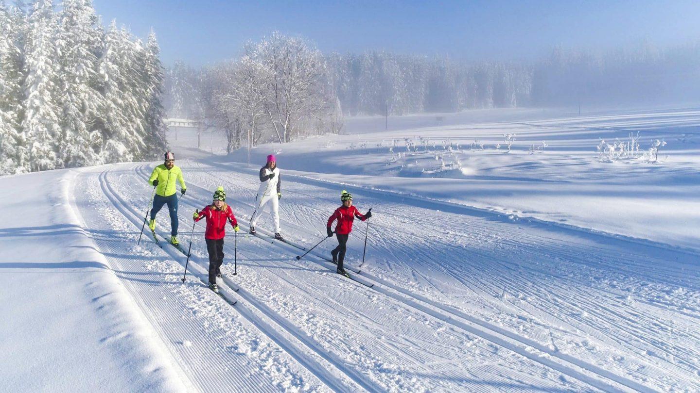 Familie beim Langlaufen in verschneiter Winterlandschaft.