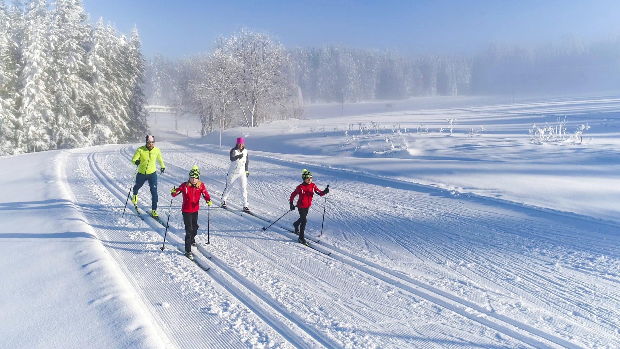 Familie beim Langlaufen in verschneiter Winterlandschaft.