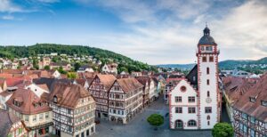 Panoramaansicht einer historischen Stadt mit Fachwerkhäusern und einem markanten Turm.