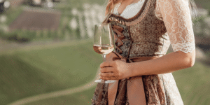 Frau in traditioneller Tracht hält ein Glas Roséwein.