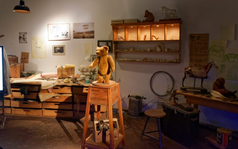 Ein Bär aus Plüsch steht auf einem Holzstuhl in einem kreativen Atelier.