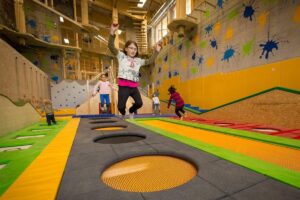 Kinder springen auf Trampolinen in einem Spielbereich.