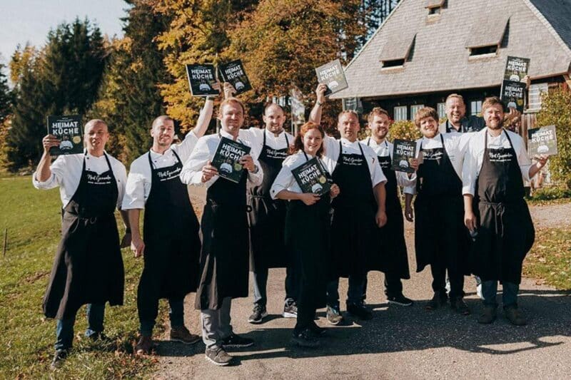 Gruppe von Köchen in Schürzen hält Kochbücher in der Natur.