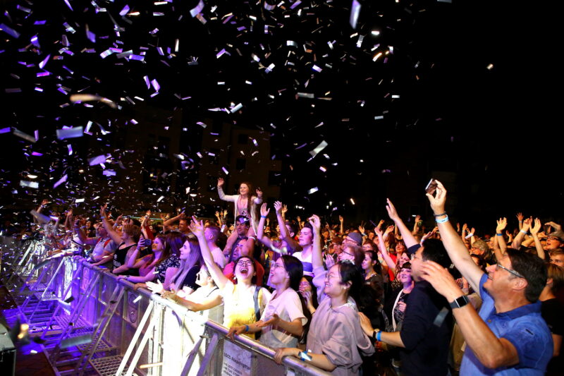 Menschenmenge feiert mit Konfetti bei einem Konzert.