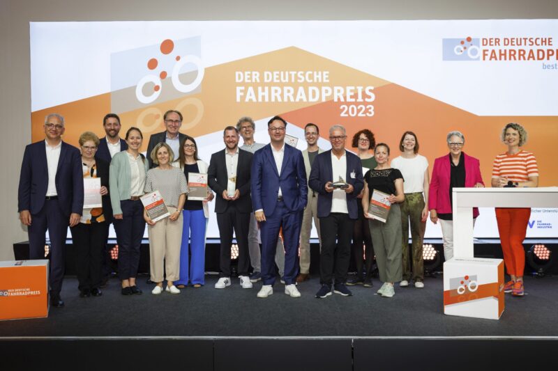 Gruppenfoto von Preisträgern des Deutschen Fahrradpreises 2023 auf einer Bühne.