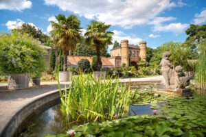 Schöner Garten mit Palmen und einer Statue von zwei Kindern am Teich.