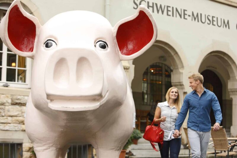 Paar vor einem großen, lächelnden Schwein im Schweine-Museum.