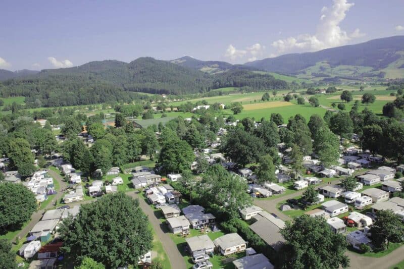 Luftaufnahme eines Campingplatzes mit Wohnmobilen und grüner Landschaft.