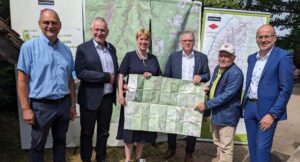 Gruppe von fünf Personen hält eine große Karte in der Hand.