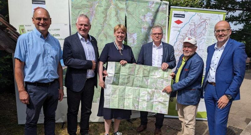 Gruppe von fünf Personen hält eine große Karte in der Hand.