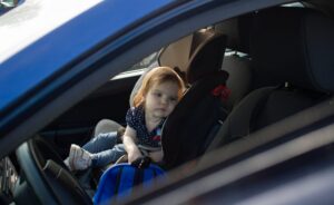 Kleines Mädchen sitzt im Auto auf dem Kindersitz.