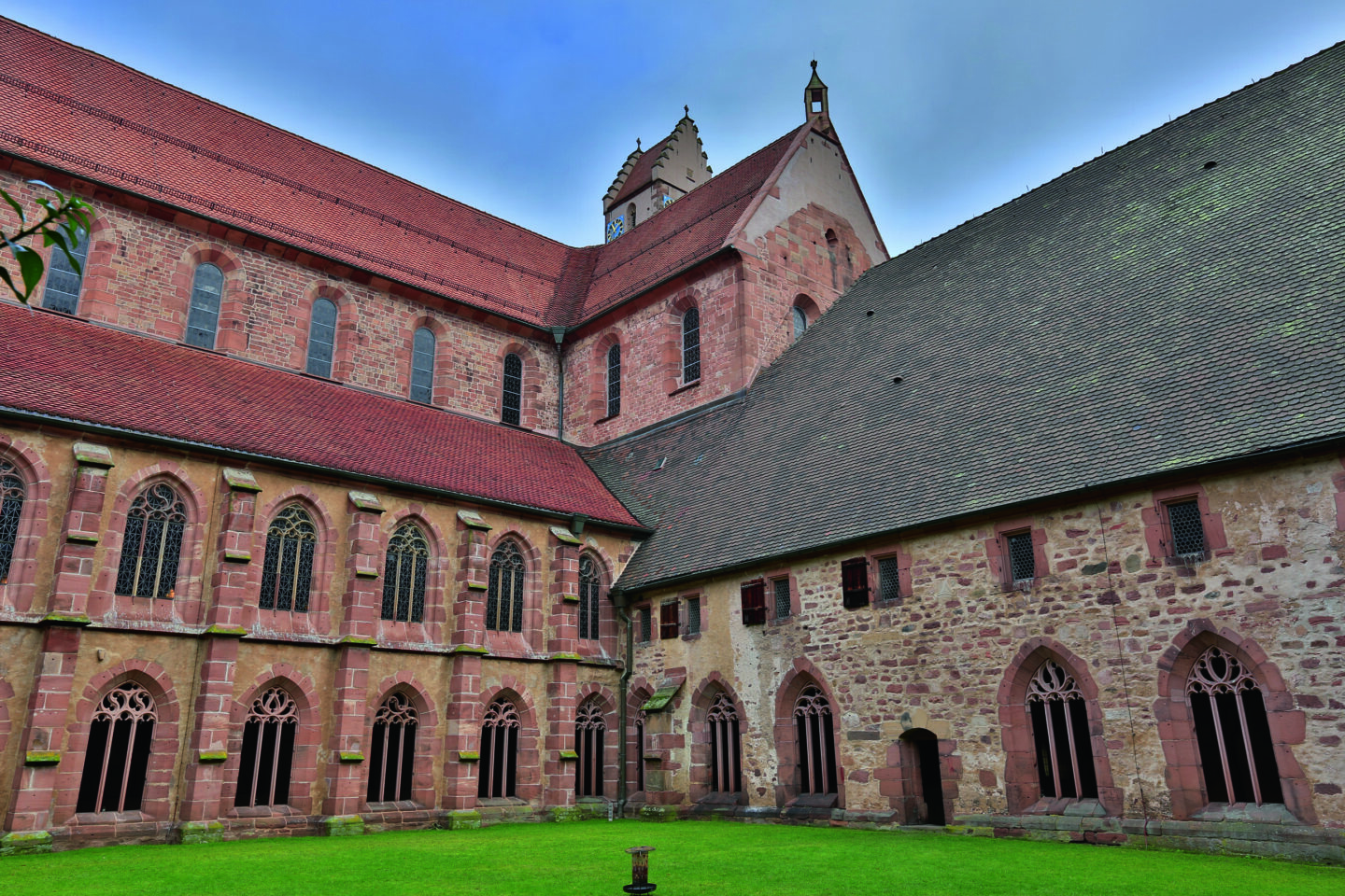Innenhof eines historischen Klosters mit roten Ziegelwänden und gotischen Fenstern.