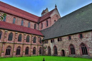 Innenhof eines historischen Klosters mit roten Ziegelwänden und gotischen Fenstern.