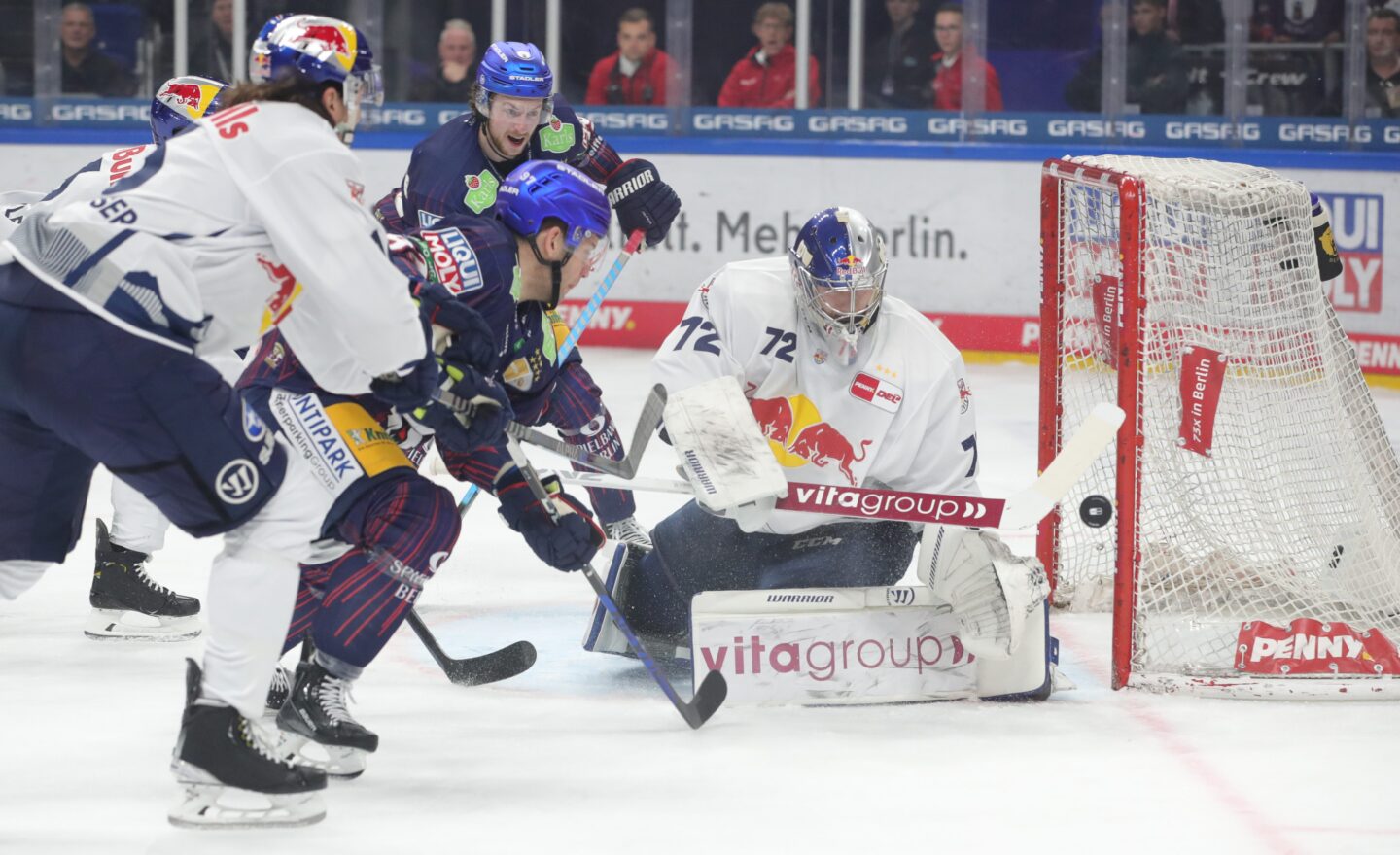 Eishockeyspiel mit Spielern und Torwart in Aktion.