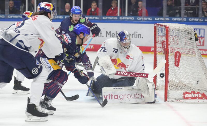 Eishockeyspiel mit Spielern und Torwart in Aktion.