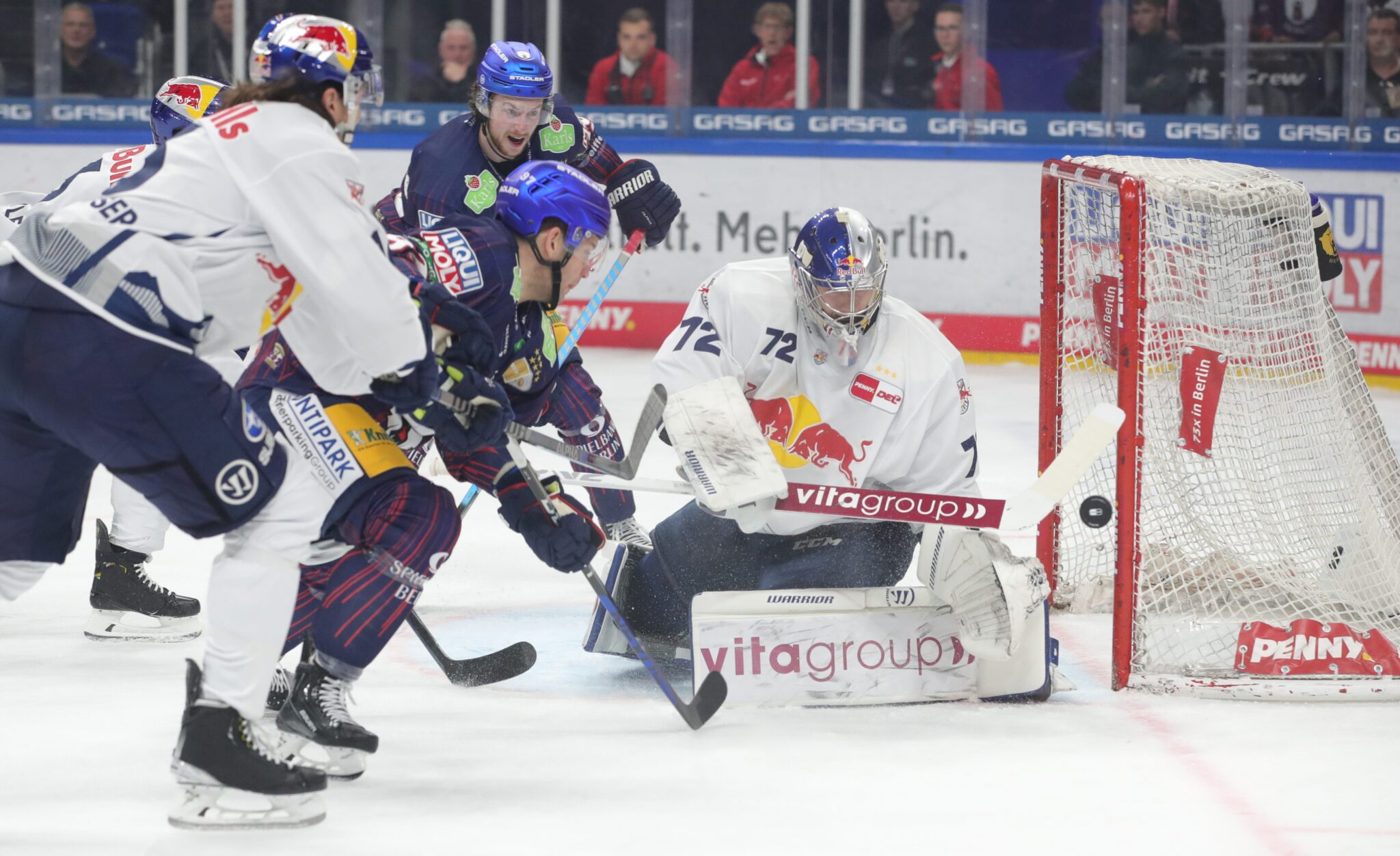 Eishockeyspiel mit Spielern und Torwart in Aktion.