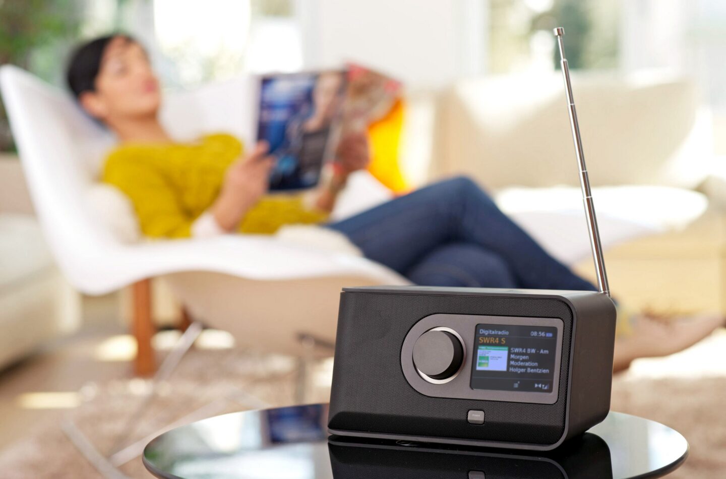 Frau entspannt sich mit einem Magazin, Radio im Vordergrund.