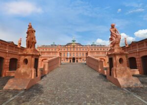 Historisches Schloss mit Statuen und gepflastertem Weg.