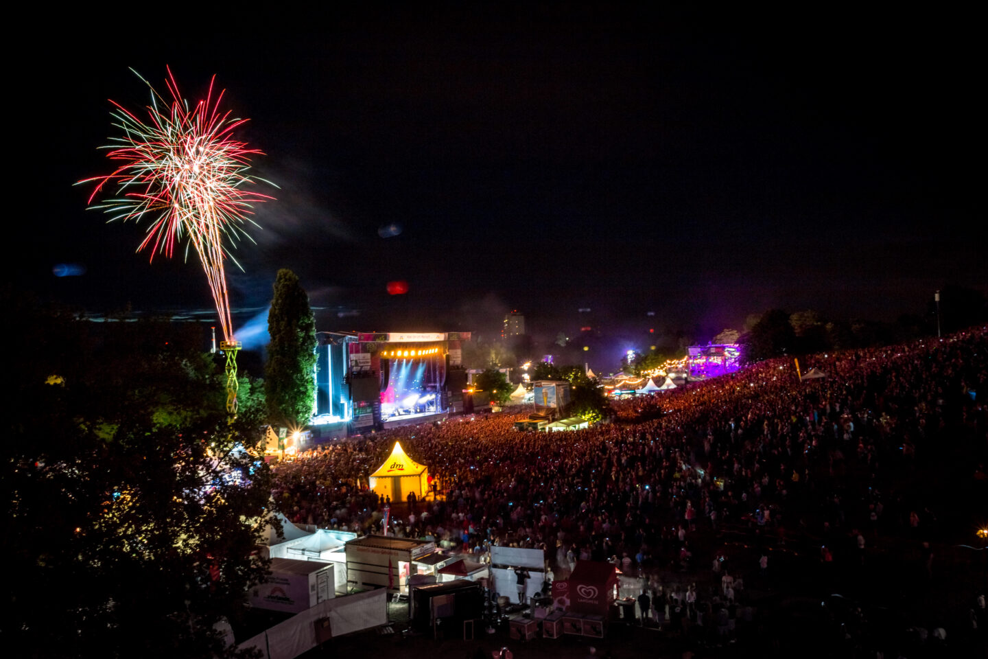 Großes Musikfestival bei Nacht mit Feuerwerk und Menschenmenge.