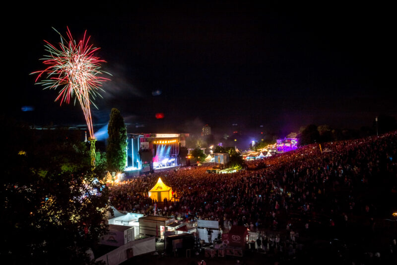 Großes Musikfestival bei Nacht mit Feuerwerk und Menschenmenge.