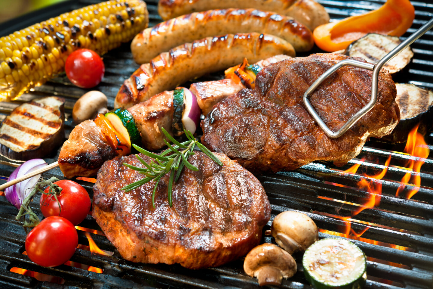 Gegrilltes Fleisch, Würstchen und Gemüse auf einem Grill.