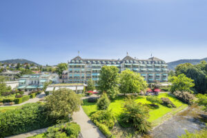 Ansicht eines eleganten Hotels mit Garten und blauen Himmel.