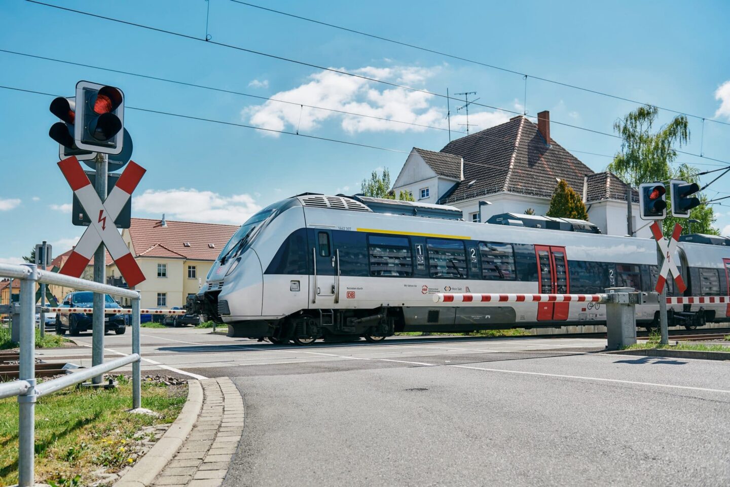 Ein Zug fährt an einem Bahnübergang mit Signalen vorbei.