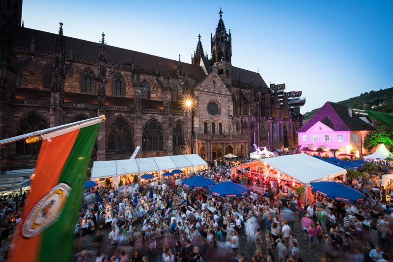 Bunte Festlichkeiten vor einer beeindruckenden Kathedrale bei Dämmerung.