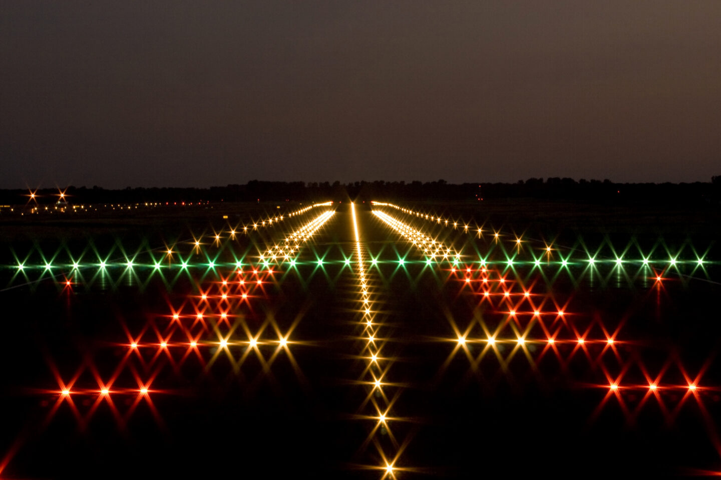 Beleuchtete Landebahn bei Nacht mit bunten Lichtern.