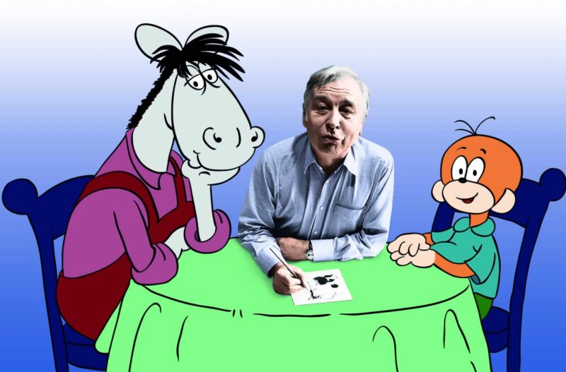 Ein Mann sitzt an einem Tisch mit zwei Cartoonfiguren.