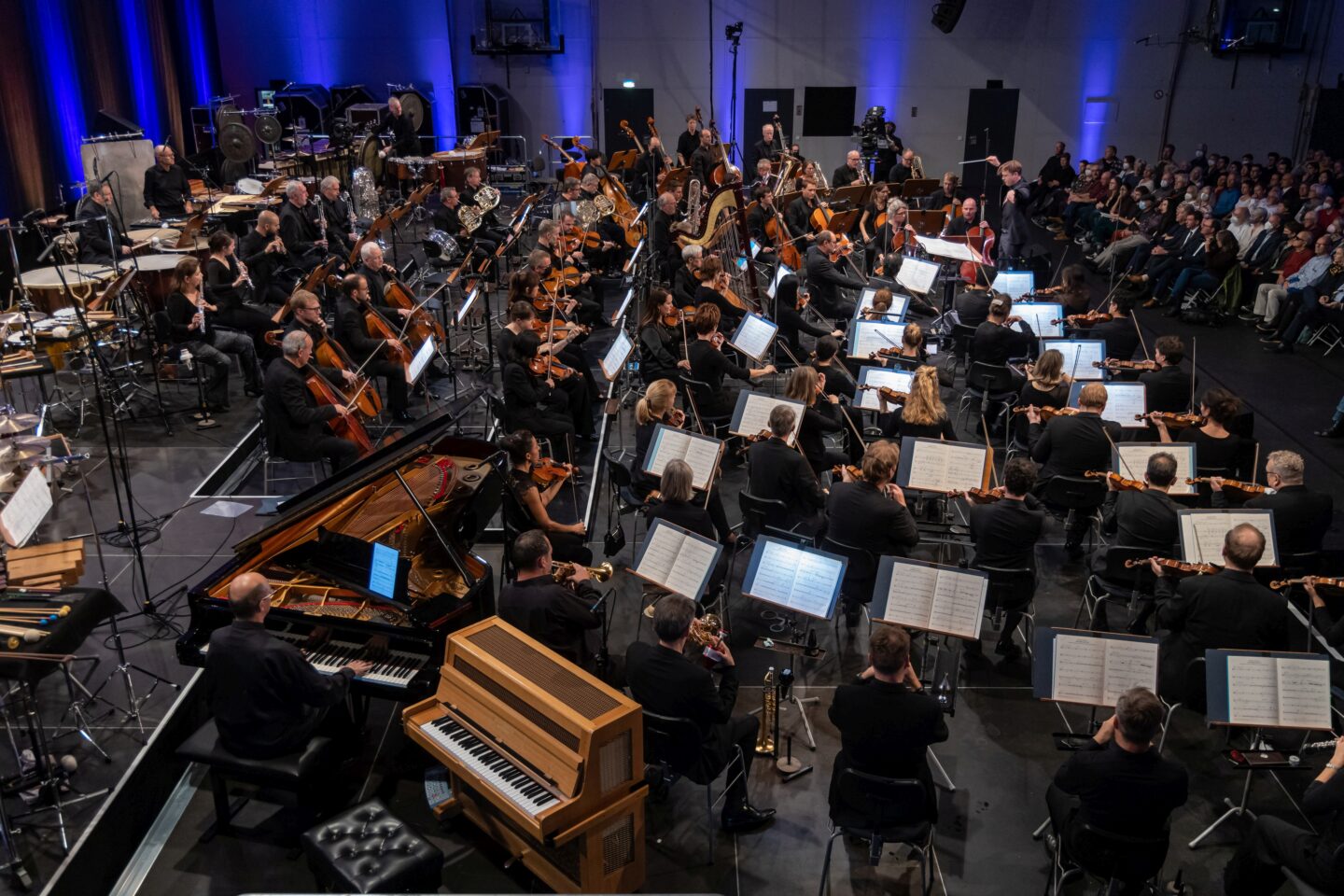 Orchester bei einem Konzert mit verschiedenen Instrumenten und Musikern auf der Bühne.