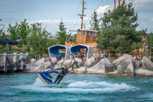 Mann fährt auf einem Jetski und springt über das Wasser.