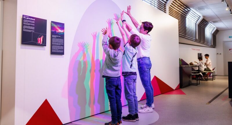 Kinder interagieren mit einer Lichtinstallation in einem Ausstellungsraum.