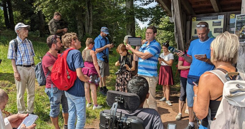Gruppe von Menschen bei einer Informationsveranstaltung im Freien.