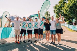 Gruppe von sechs Personen posiert fröhlich mit Flaggen und Banner.