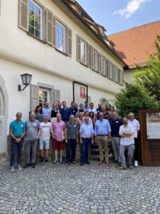Gruppe von Männern vor einem historischen Gebäude im Freien.