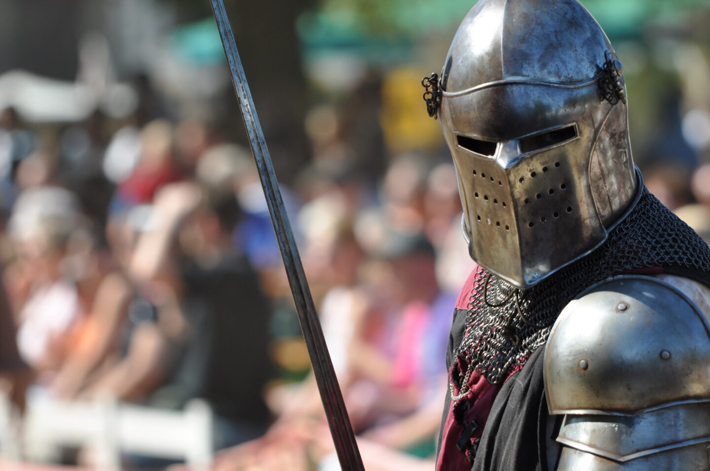 Ritter in Rüstung mit Speer vor Publikum.