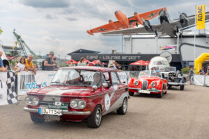 Oldtimer-Rallye mit mehreren klassischen Autos und Zuschauern.
