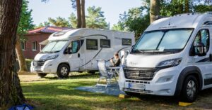 Zwei Wohnmobile auf einem Campingplatz im Grünen.