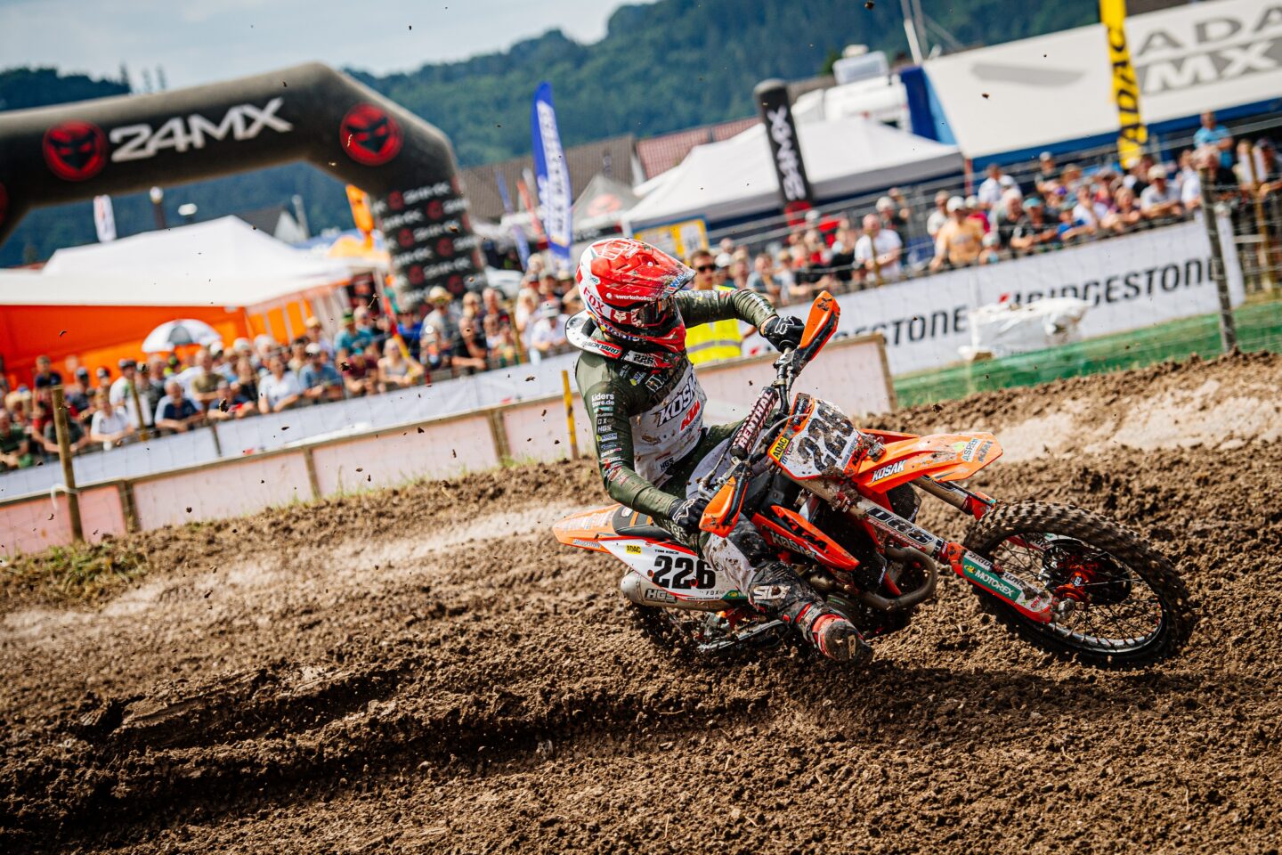 Motocrossfahrer auf einer Strecke mit Zuschauern im Hintergrund.