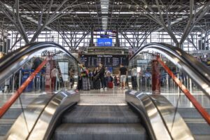 Blick auf einen modernen Flughafen mit Reisenden und Abflugtafel.
