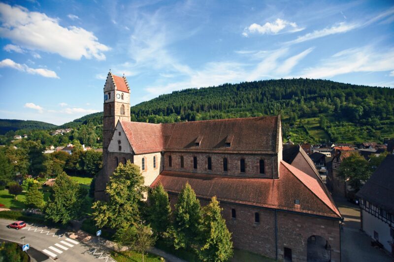 Historische Kirche mit Turm und grüner Umgebung.